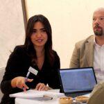 Persone al Marmomac discutono di pietra naturale con brochure e laptop.